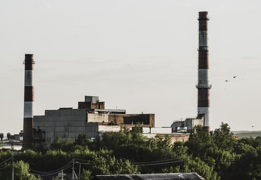 red and white industrial building with green trees and cloudy sky
