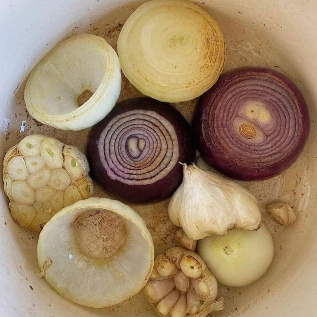 Halved onions and garlic in a ceramic pot