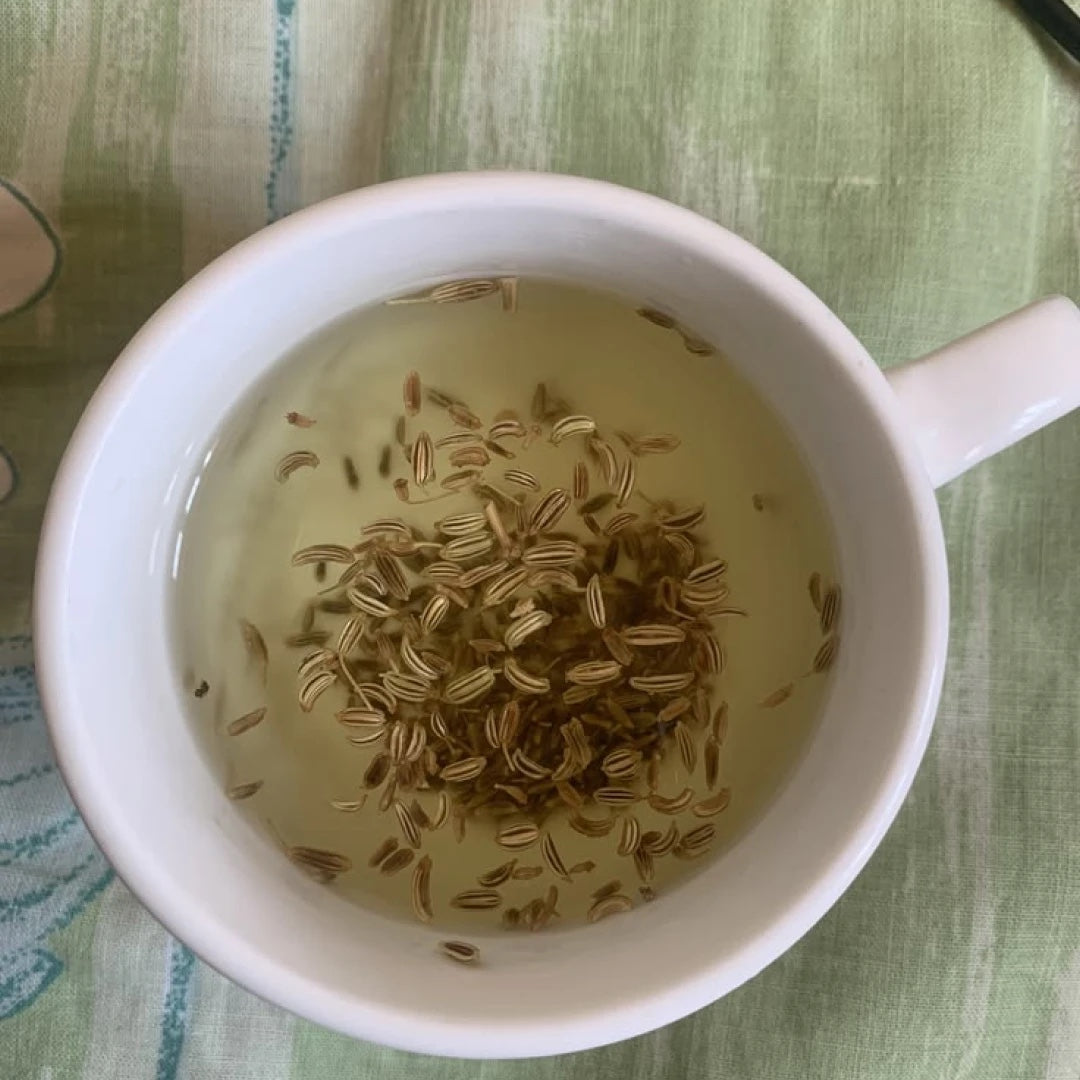 Fennel seeds steeping in a white cup on green linen