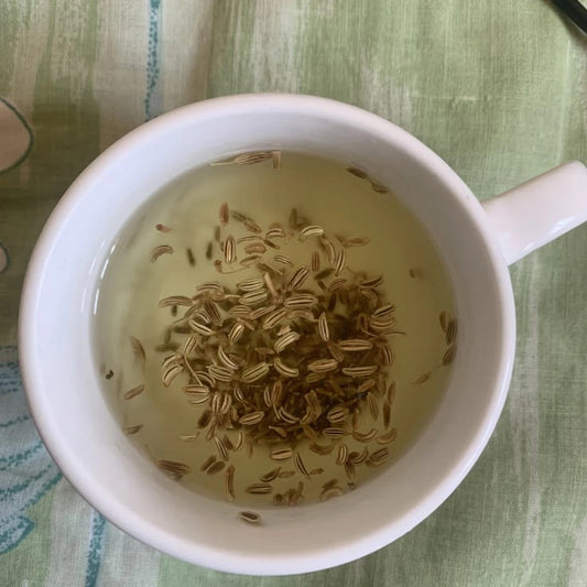 Fennel seeds steeping in a white cup on green linen